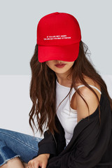 Cropped upward shot of a dark-haired girl, wearing red baseball cap with lettering 