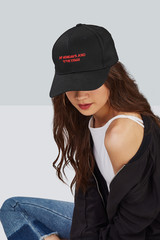 Cropped upward shot of a dark-haired girl, wearing black baseball cap with lettering 