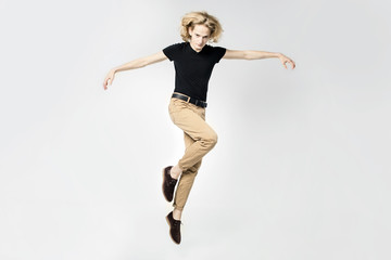 Fototapeta na wymiar A frantic and expressive jump, hair scatter in different directions. Portrait of a jumping man on a light background.