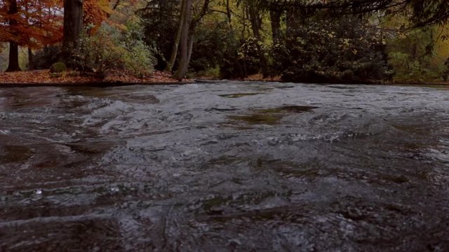 A fast Eisbach stream / river on an autumn / fall day in the Englisher Garten park, Munich, Germany