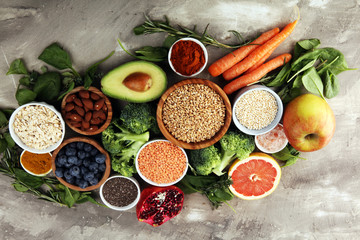 Healthy food clean eating selection: fruit, vegetable, seeds, superfood, cereals, leaf vegetable on rustic background