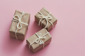 Set of parcels wrapping in brown craft paper and tie hemp string. Package. Delivery service. Online shopping. Your purchase. Gift box on a table. Pink solid background.