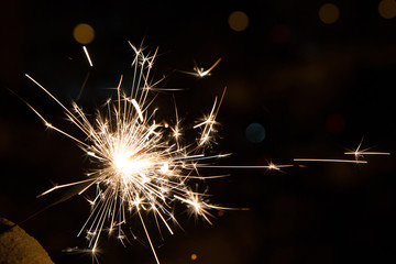 Bengal fire sparkles against the background of city lights, blurred bokeh