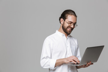 Handsome bearded man wearing glasses using laptop computer.