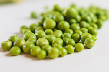 On a white background scattered with fresh green peas, there is a place for an inscription.