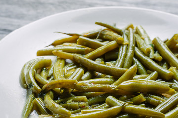 Cooked green beans on the white ceramic plate, close up shot
