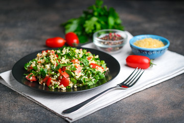 Traditional oriental salad Tabbouleh with bulgur and parsley on a dark background copy space.