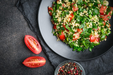 Traditional oriental salad Tabbouleh with bulgur and parsley on a dark background top view copy space.