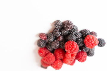 Fragrant sweet red and black raspberries on a white background.