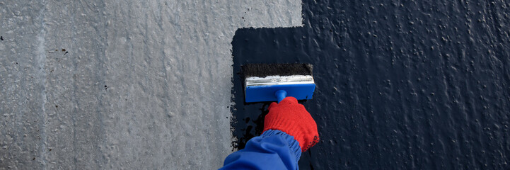 Worker applies bitumen mastic on the foundation