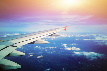 Obraz premium Airplane wing with sunrise in light flare by looking through the airplane window. - Image
