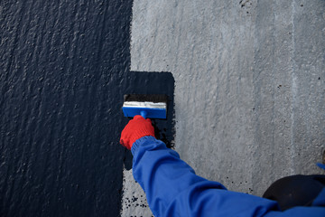 Worker applies bitumen mastic on the foundation