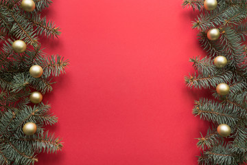 Christmas frame with fir branches, golden balls on red background. Space for text, view from above, flat lay. Happy New Year.