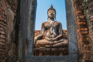 Fototapeta premium Seated buddha in the ruins of the mondop close to main buddha of Wat Si Chum in Sukhothai Historic Park Thailand