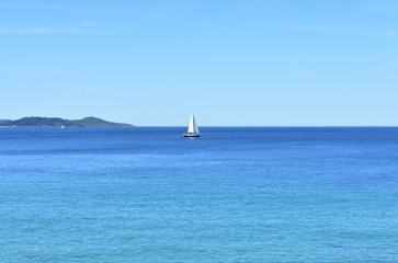 Fototapeta premium Bay with blue sea and sailing boat on a sunny day. Sanxenxo, Rias Baixas, Pontevedra, Spain.
