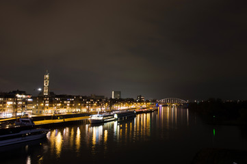 Arnhem in the Netherlands, with St. Eusebius church and the John Frost bridge at night with in the foreground the river Rhine
