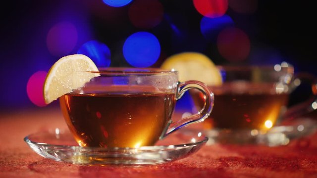 Two cups with aen stand on the table against the background of the blurry lights of a Christmas tree