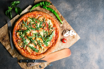Traditional Italian pizza with eggplants, mozzarella, basil and tomatoes on a dark background top...