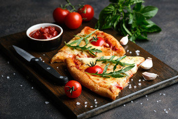 Traditional Italian pizza with eggplants, mozzarella, basil and tomatoes on a dark background copy space.