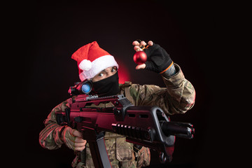 the girl in military overalls airsoft posing with a gun in his hands on a dark background in the...