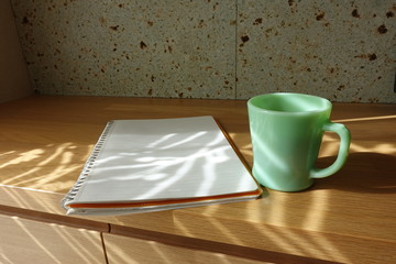 木製テーブルに置かれたコーヒーカップとノート　cup of coffee and book on wooden table