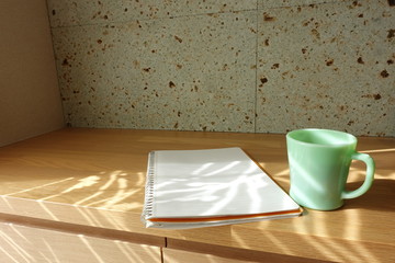 木製テーブルに置かれたコーヒーカップとノート　cup of coffee and book on wooden table