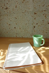 木製テーブルに置かれたコーヒーカップとノート　cup of coffee and book on wooden table