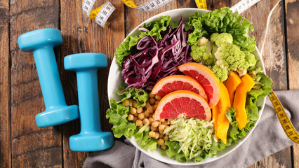 vegetarian salad with meter and dumbbell, healthy food- diet food concept