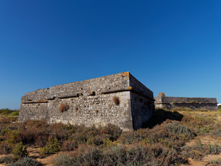 Fototapeta na wymiar An old ruined and abandoned fort lying on the land behind the beach at Ilha da Culatra on Portugals Algarve Coast.