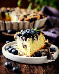 Cake with blueberries on a dark wooden background, still life