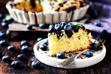 Cake with blueberries on a dark wooden background, still life