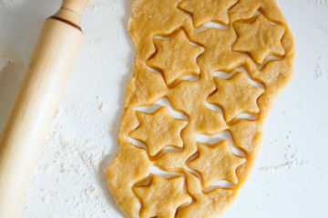Baking christmas ginger cookies: rolled dough on the table with cutted stars and rolling pin