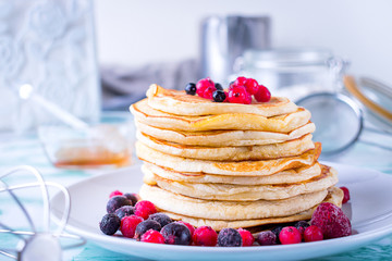 Pancakes with berries with pastry objects in the background.