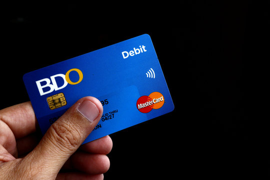 Hand holding a debit or ATM Mastercard with EMV chip of BDO