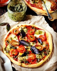 Pizza margarita with pesto on a dark wooden background