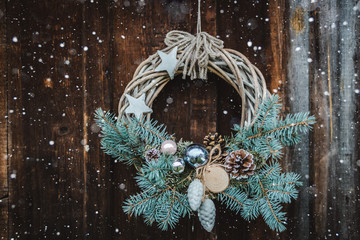 Christmas wreath on rustic wooden door background of blue tree. - Powered by Adobe