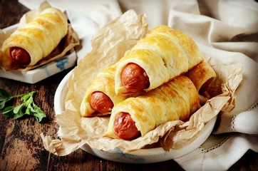 Sausages in the dough on a plate on a dark wooden table