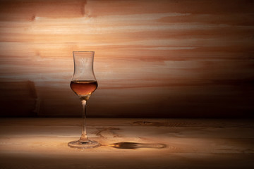 A glass of whiskey against a brown Board