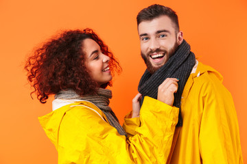 Obraz premium Loving couple posing in yellow raincoats isolated