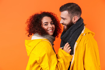 Loving couple posing in yellow raincoats isolated