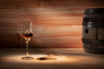 Grappa glass near an oak barrel