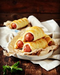 Sausages in the dough on a plate on a dark wooden table