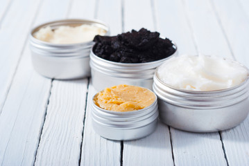 shea, macadamia nut and coffee butter, black cosmetic mud on white wooden table background