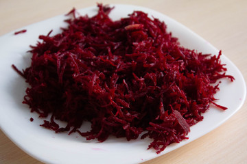 finely grated beetroot finely for salad or soup on a white plate