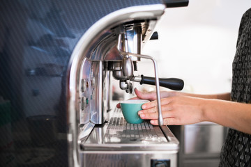 Woman making a drink at an industrial coffee maker in a cafe