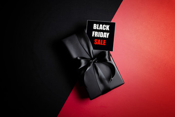 Top view of Black Friday Sale text with black gift box isolated on black background.