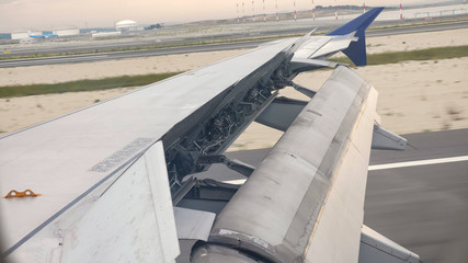 Plane landing on the runway, detail of wing, spoilers and ailerons. Aircraft wing outside board...
