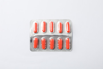 Red capsule pills in blister pack on white background, top view