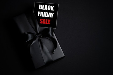 Top view of Black Friday Sale text with black gift box isolated on black background.