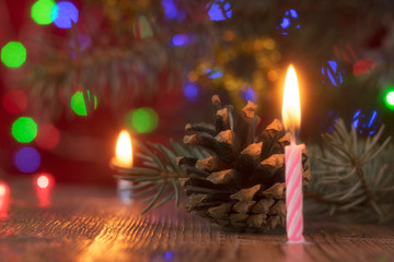 Composition from a still life for the holiday of Christmas and New Year. Fir cones, garlands and candles, as well as a Christmas tree with Christmas decorations